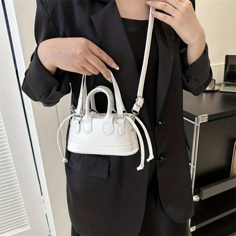 Person holding a white handbag with a black background
