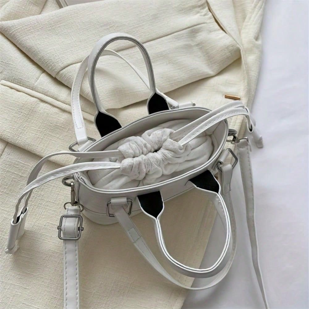 White handbag with black accents on a light beige fabric background