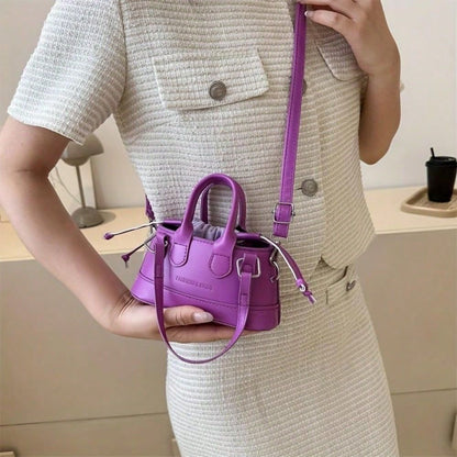 Person holding a small purple handbag with a matching strap.